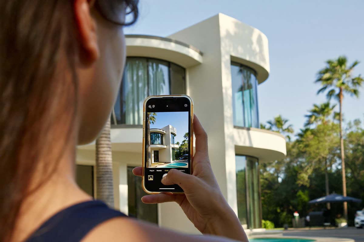 Homeowner photographing their glass-walled home with a phone